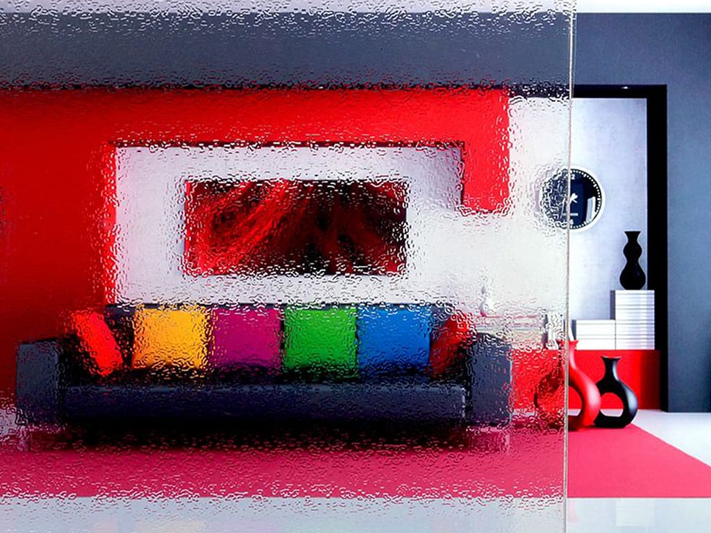 glass like distortion film applied to a glass partition. The film is obscuring a multicolored couch and a red wall behind it.
