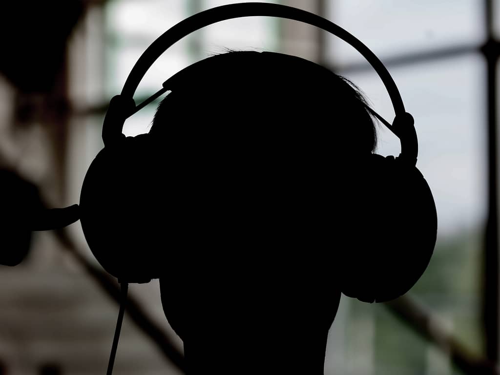Silhouette of a person with headphones on eavesdropping.