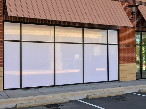 Storefront glass with opaque window film applied to it in order to obscure the contents.