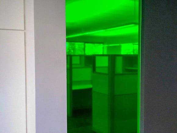 Glass sidelite with green colored window film applied to it.